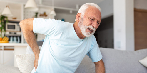 Senior elderly man touching his back, suffering from backpain, sciatica, sedentary lifestyle concept. Spine health problems. Healthcare, insurance